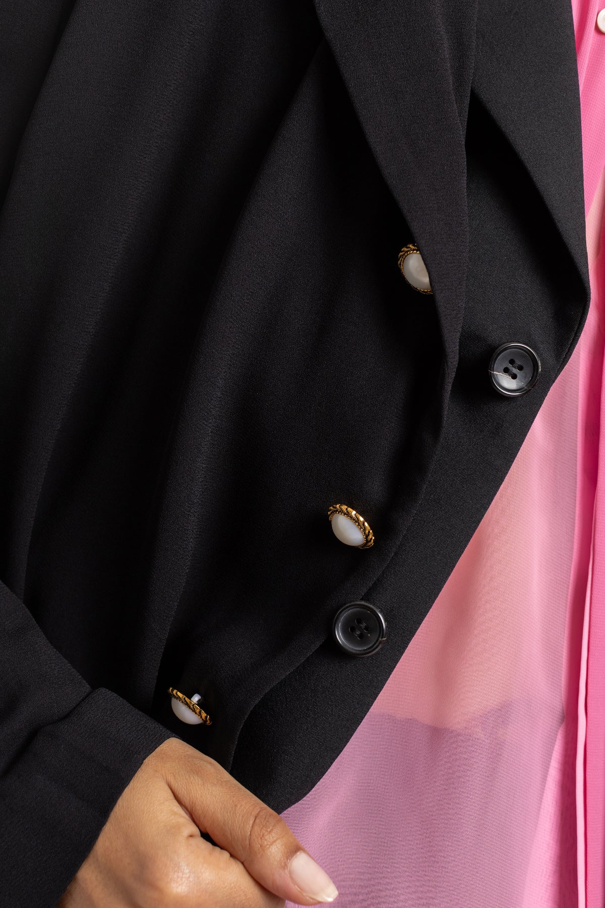 Detalhe do punho do casaco Comme des Garçons preto botões nacarados dourados e pretos sobrepostos em forro rosa