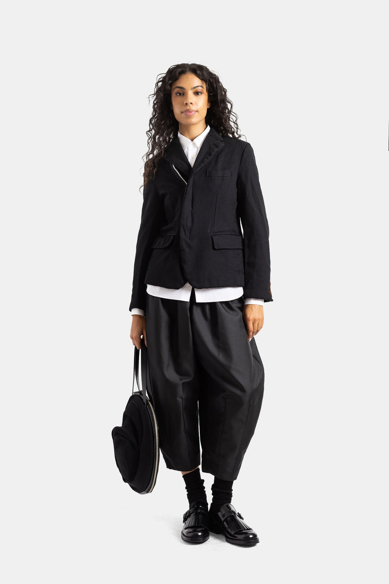 Look total negro Comme des Garçons mujer: sarouel corto holgado, blazer y mocasines de charol con flecos