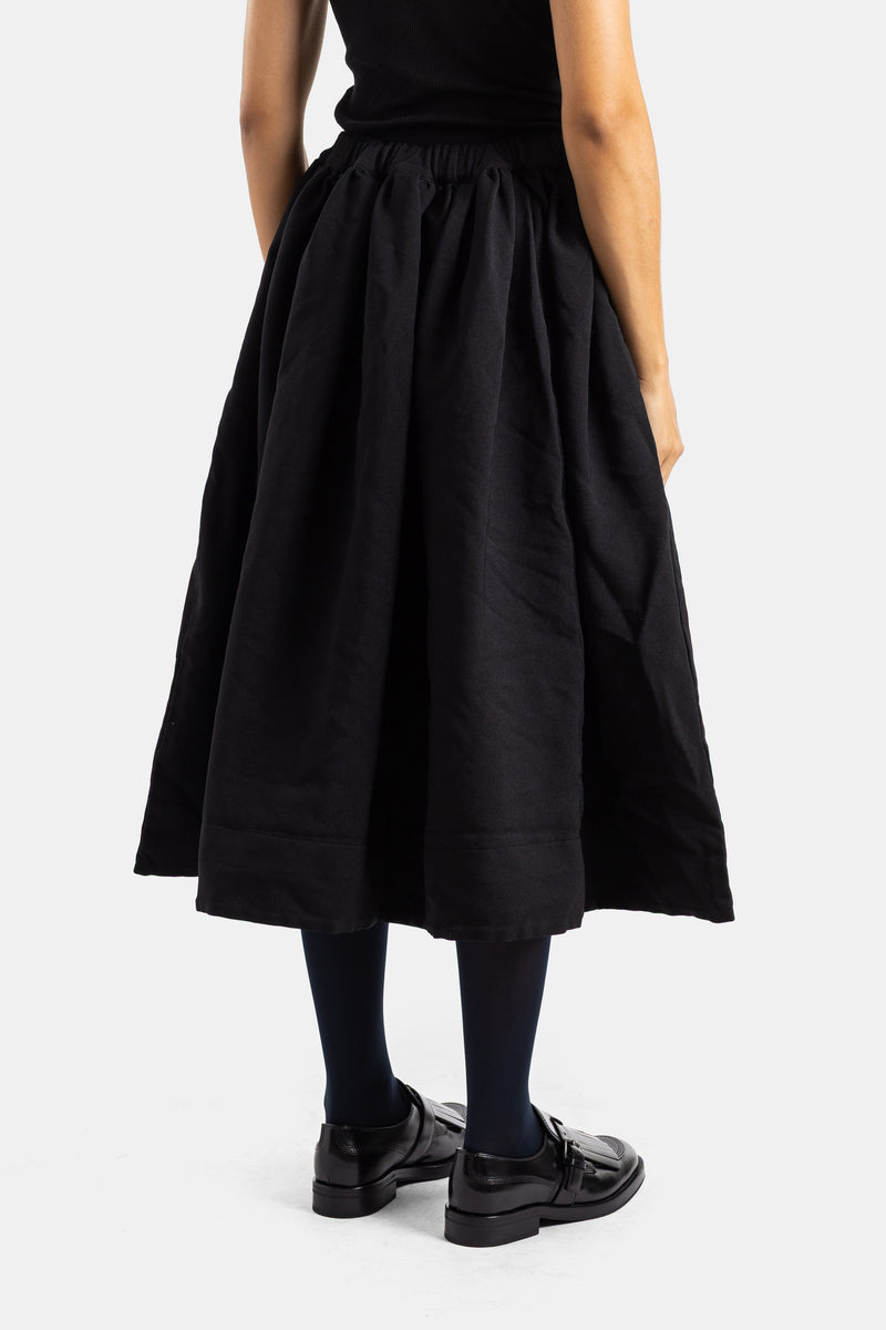 Falda midi negra y amplia de Comme des Garçons con espalda fruncida, cintura elástica y mocasines de charol.