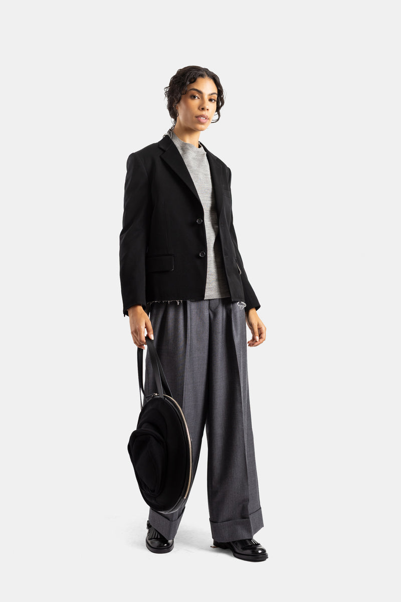 Blazer Comme des Garçons de lana negra con pantalón ancho gris y mocasines negros, look sastre para mujer.