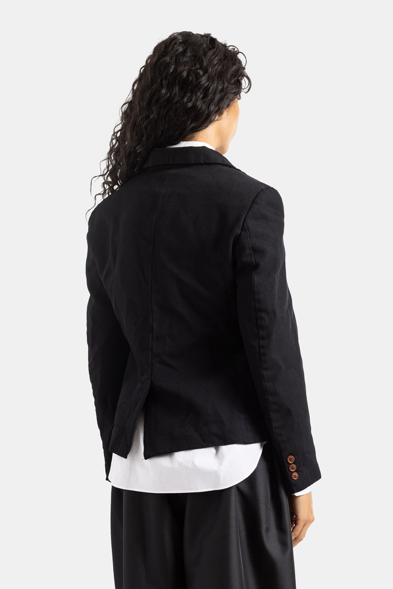 Chaqueta de sastre negra Comme des Garçons vista trasera, botones caramelo en manga, corte corto y sutil