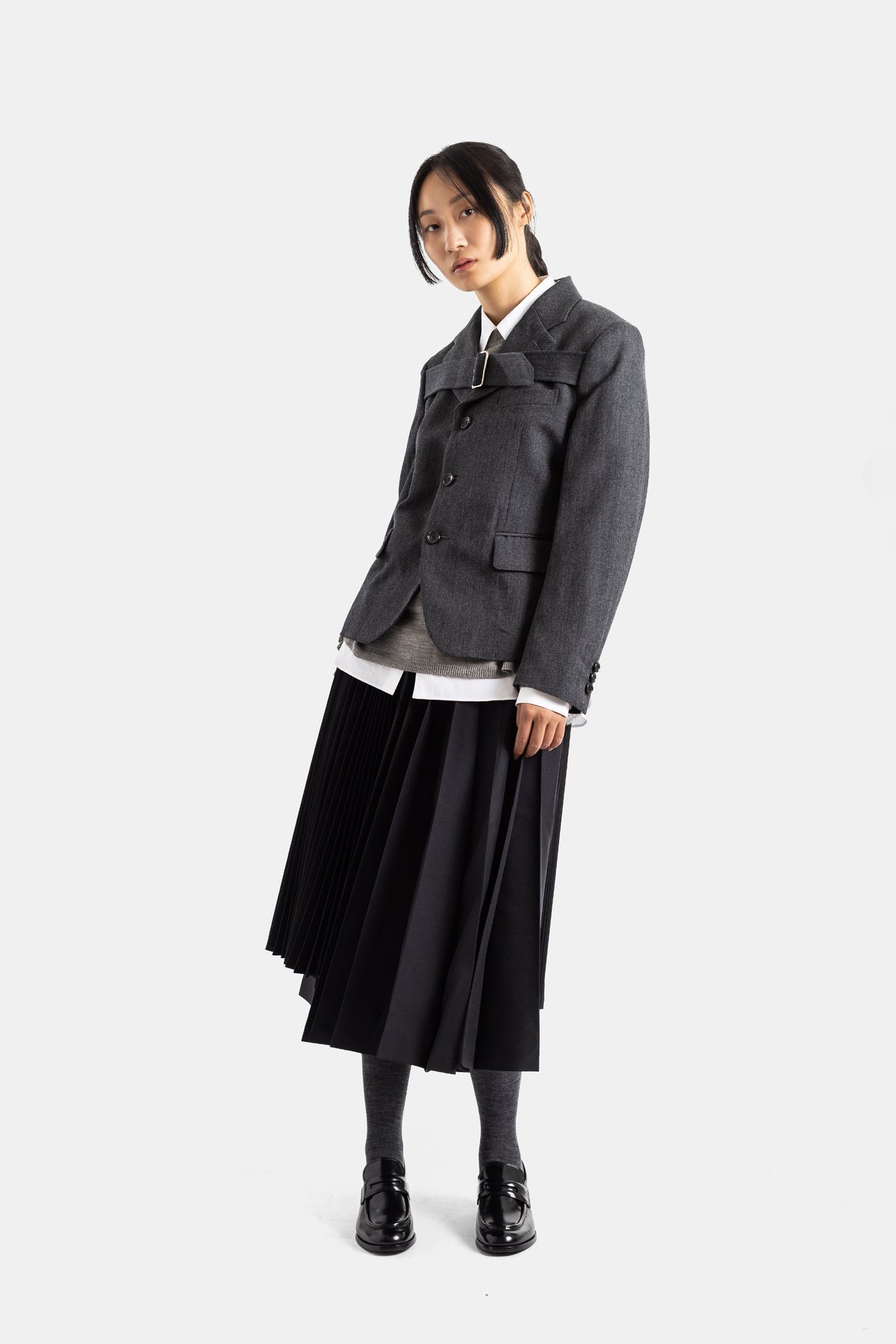 Comme des Garçons veste courte laine grise portée avec jupe midi plissée noire et mocassins vernis, look femme structuré