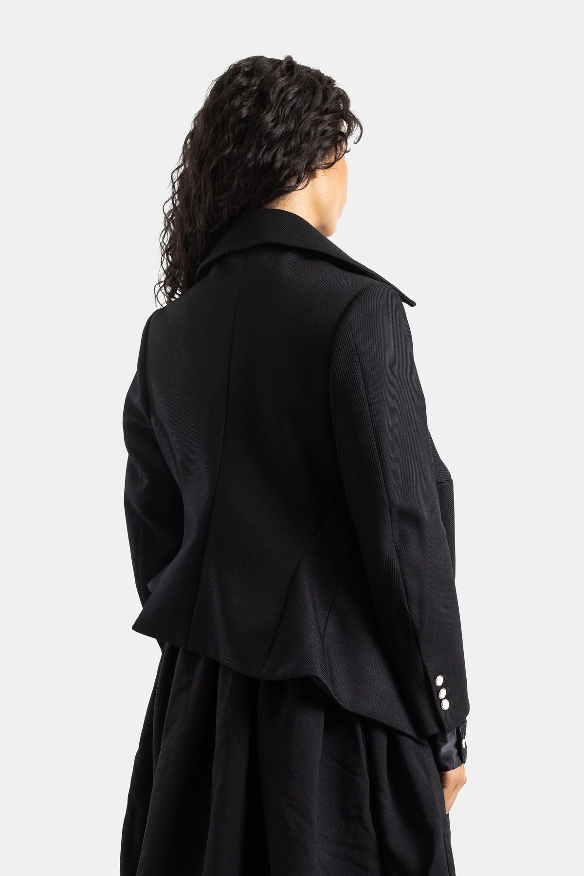 Chaqueta corta negra Comme des Garçons vista trasera desestructurada con costuras y acabados nacarados
