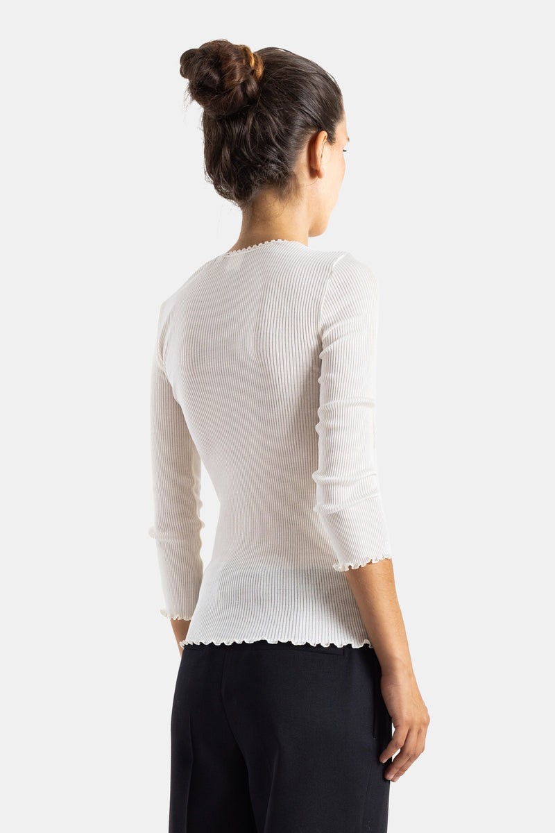 Chloé top jersey côtelé blanc, vue dos, bun élégant, transparence légère de la maille et ourlet ondulé