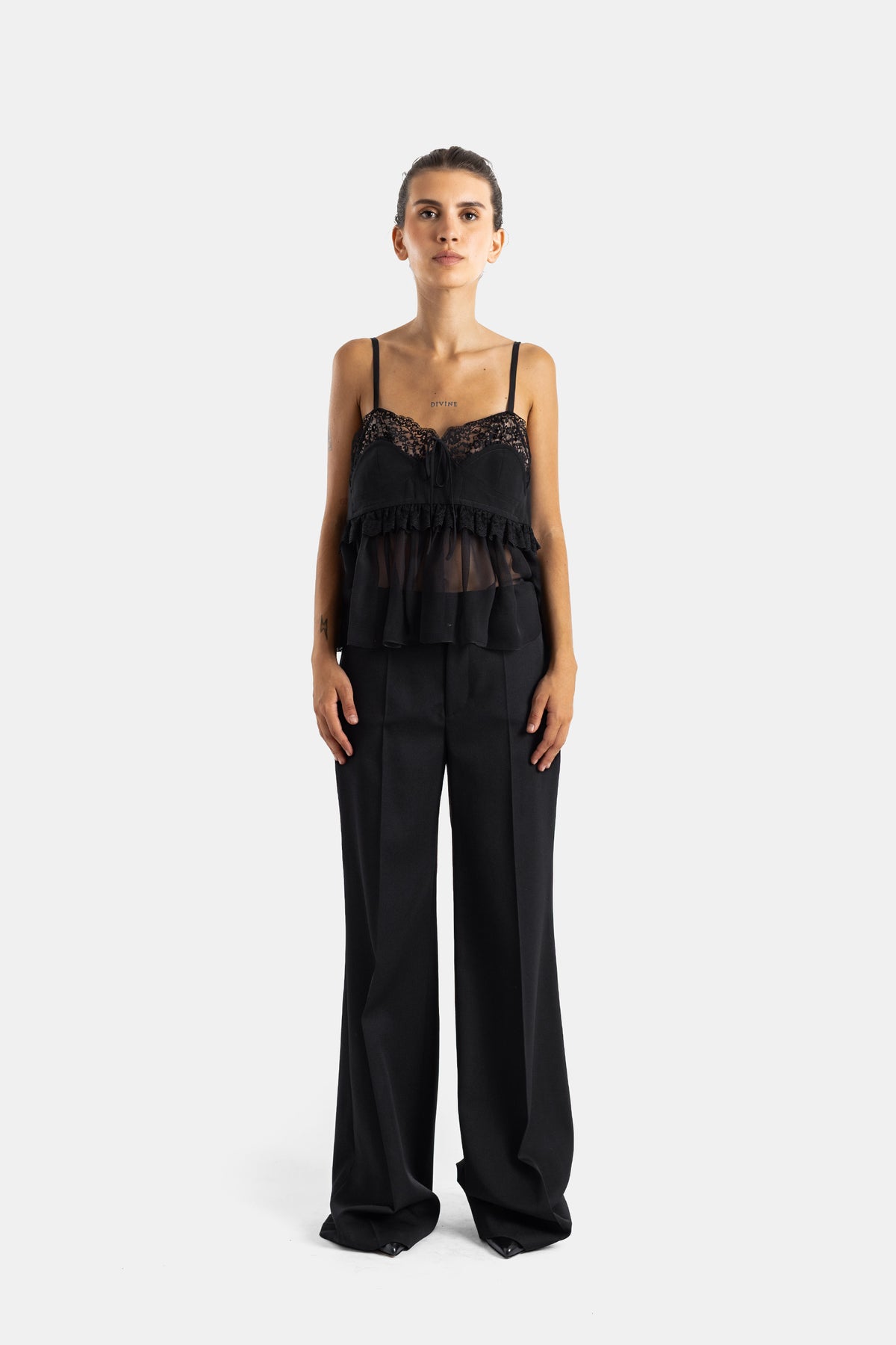Chloé pantalon évasé noir porté avec top en dentelle, silhouette complète jambe droite tombante