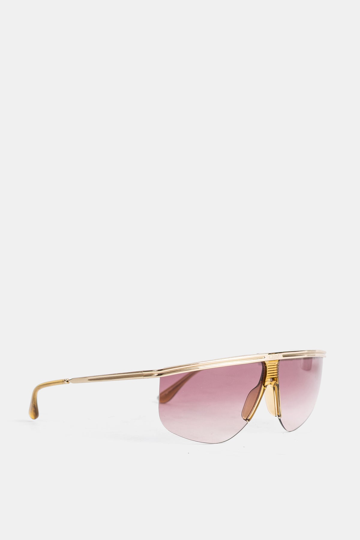 Perfil de las gafas de sol Chloé para mujer con fina patilla dorada, terminal de carey y cristales rosa degradados.