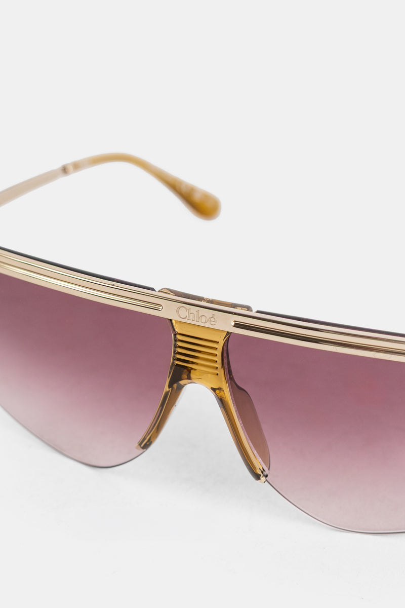 Gafas de sol de máscara Chloé para mujer con puente dorado estriado, logo grabado y cristales rosa-malva degradados.