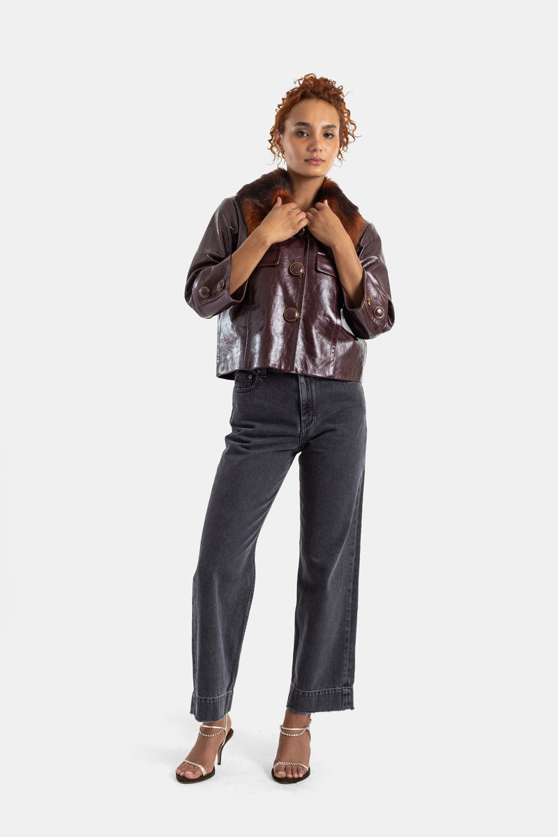 Vaqueros negros lavados Chloé con chaqueta de cuero acharolado marrón y cuello de pelo, look de otoño.