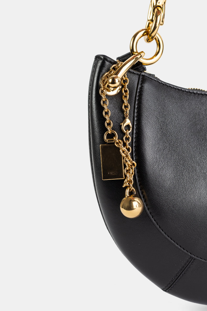 Chloé Banana gros plan quincaillerie dorée, chaîne fine à pendentif sphère et plaque logo sur cuir noir