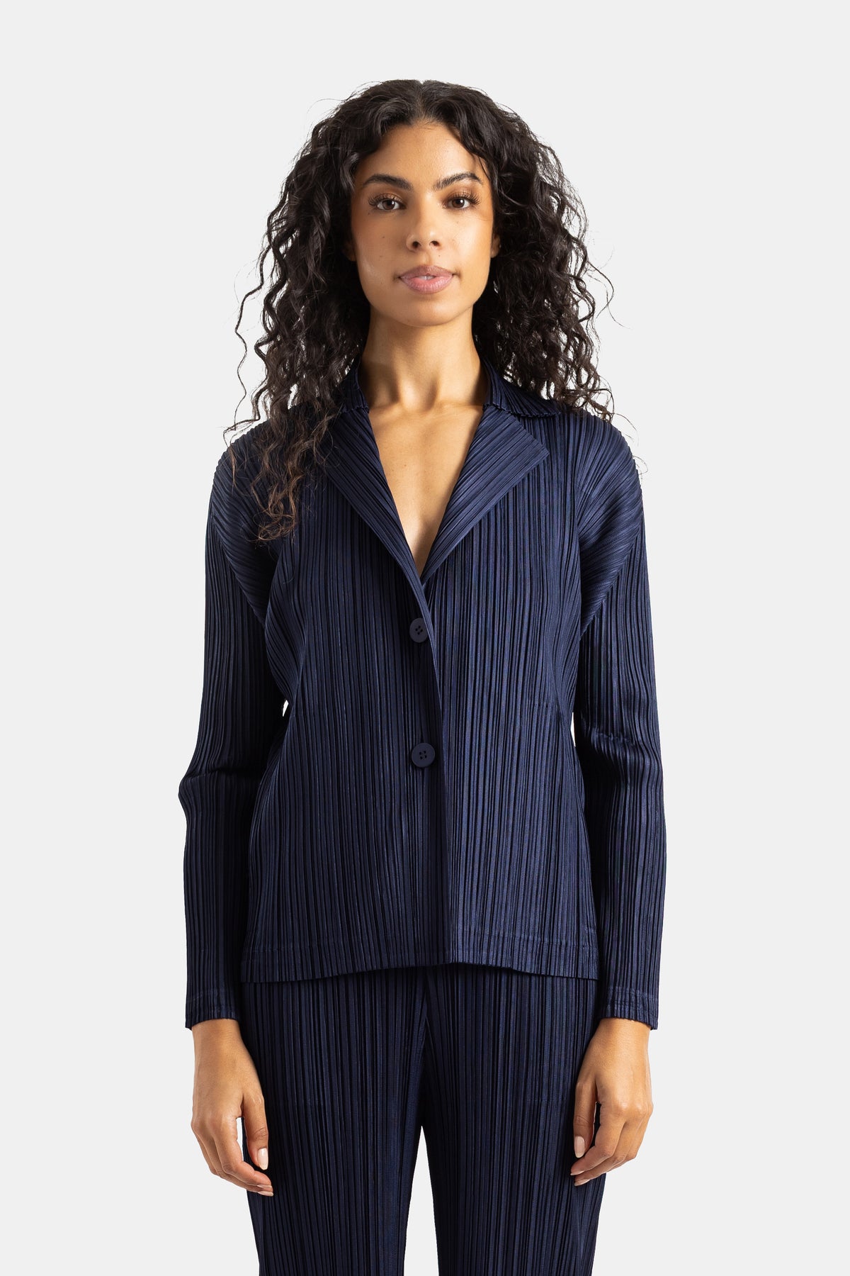 Pleats Please Issey Miyake: kurze plissierte Jacke mit Reverskragen und langen Ärmeln in elegantem Marineblau.