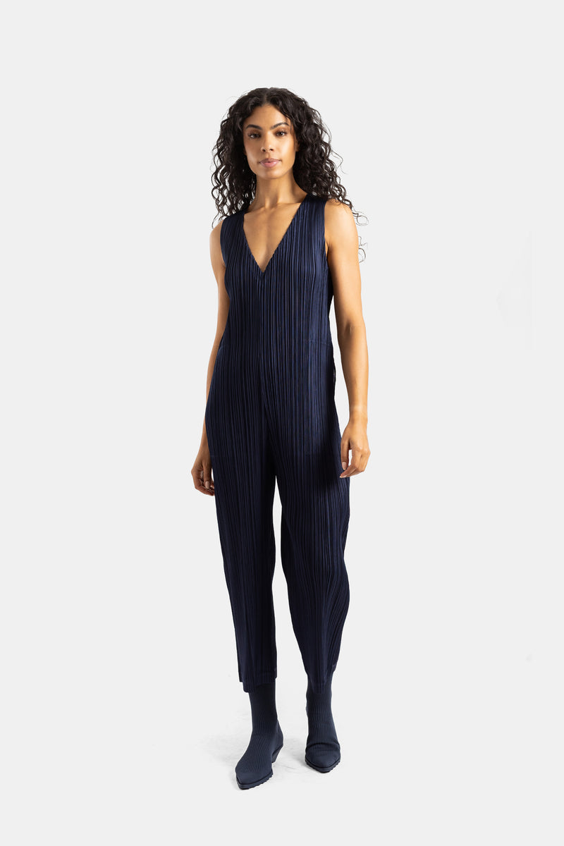 Mono plisado azul marino Pleats Please Issey Miyake con botines a juego y textura vertical estructurada.
