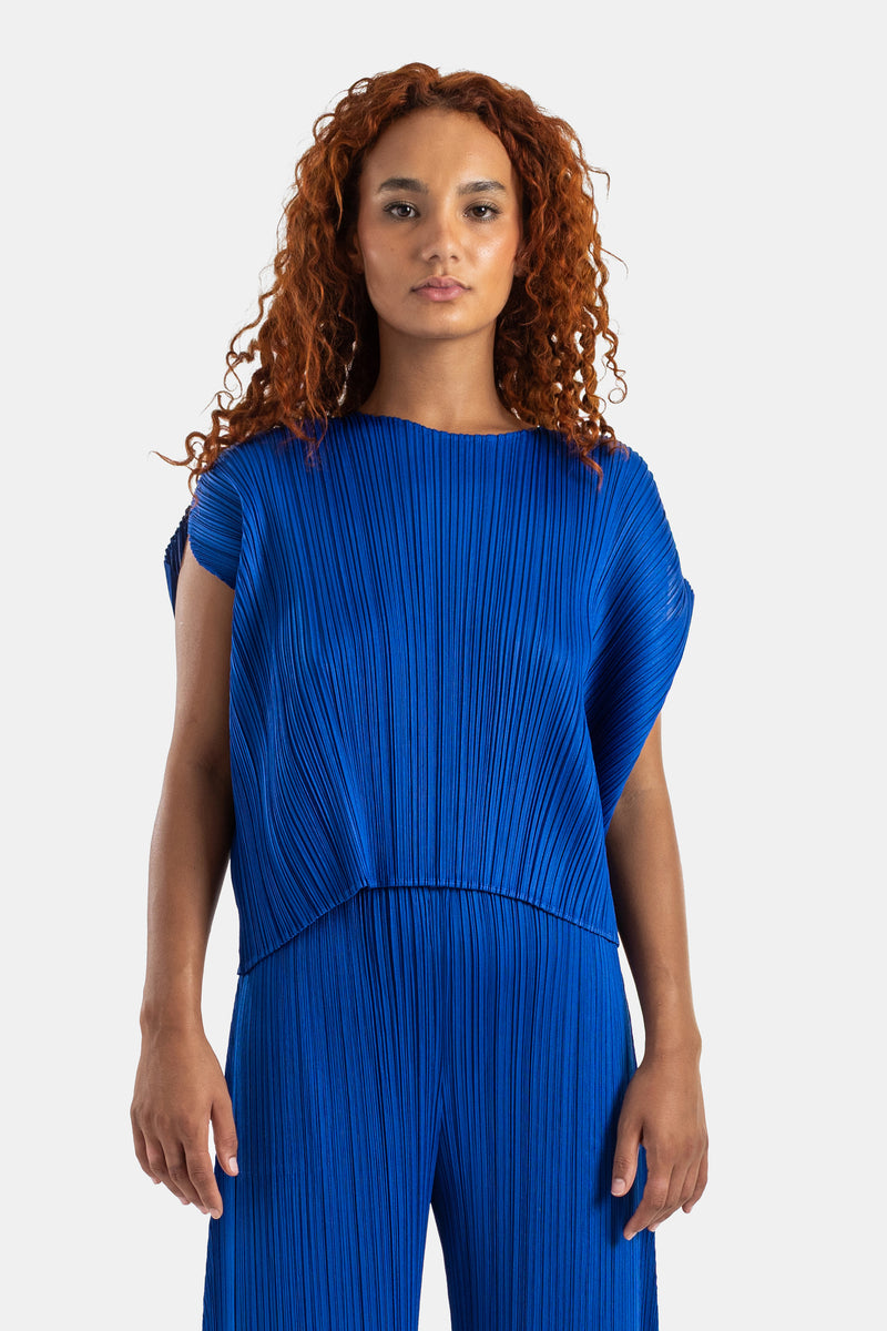 Pleats Please Issey Miyake 브랜드의 로열 블루 컬러 오버사이즈 플리츠 라운드넥 반팔 탑 제품으로, 독창적인 미세 플리츠 주름과 감각적인 실루엣이 돋보이는 여성용 하이엔드 데일리 탑 셔츠웨어 패션 스타일.