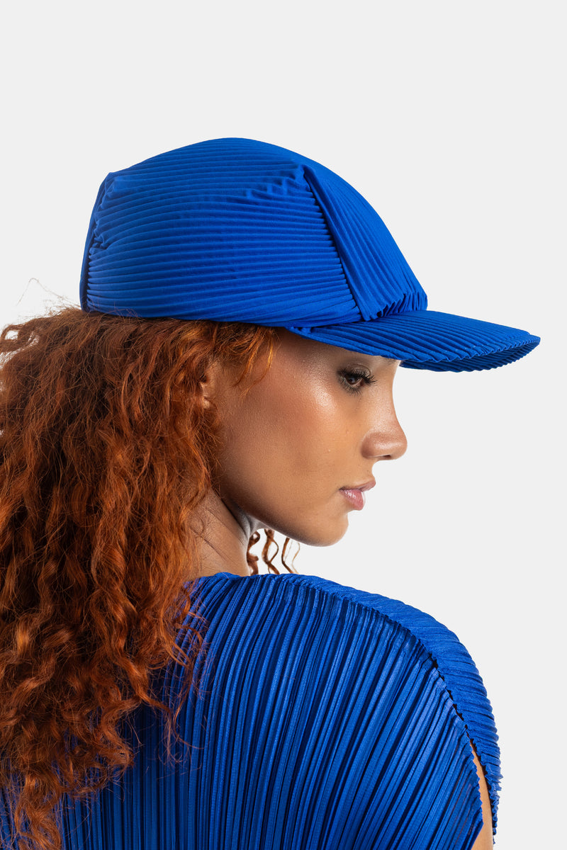 Pleats Please Issey Miyake casquette et top plissés bleu roi coordonnés vue trois-quarts dos cheveux roux