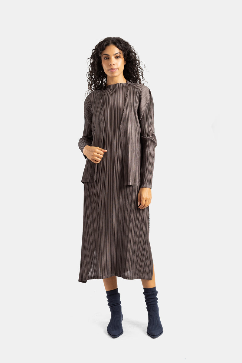 Conjunto de cárdigan y falda plisados Pleats Please Issey Miyake marrón taupe con botines en color navy.