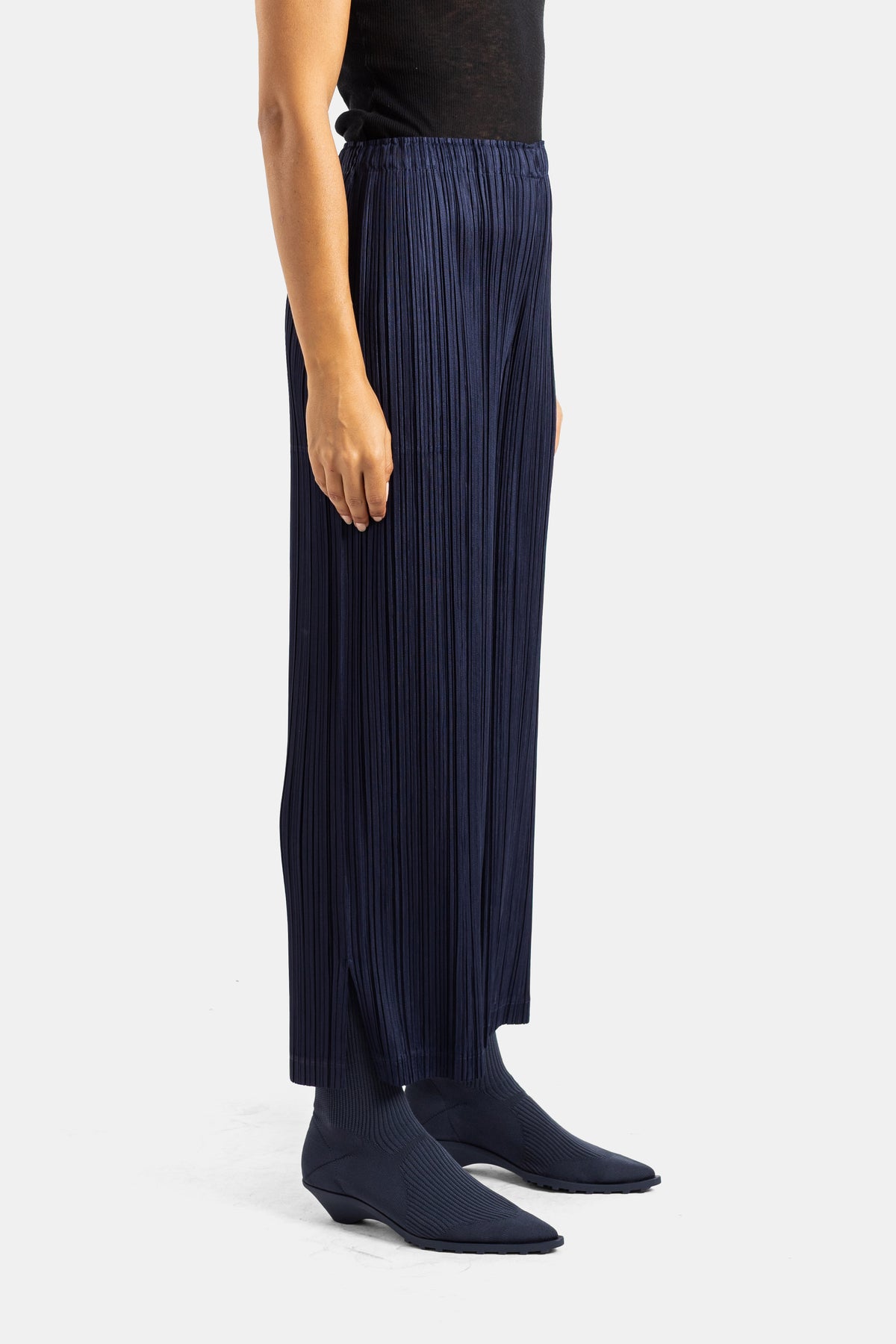 Pantaloni plissettati blu navy Pleats Please Issey Miyake, vista laterale con spacchi e taglio fluido, donna.