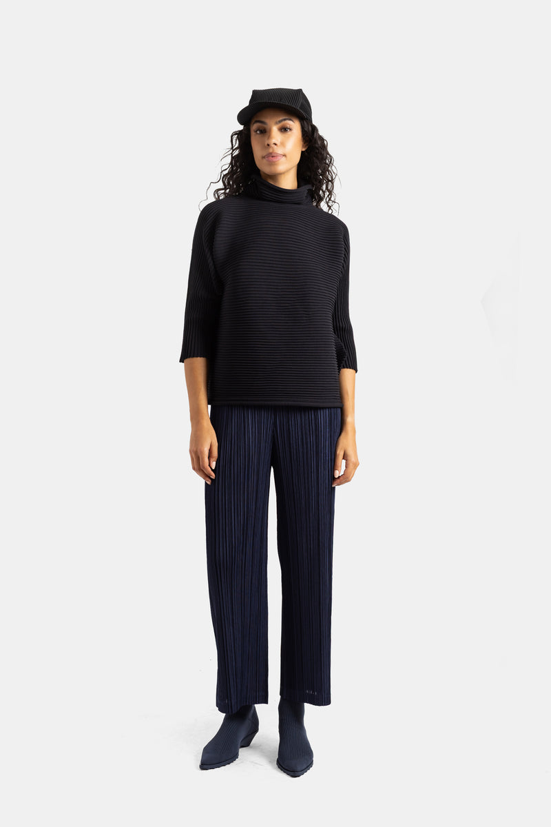 Pantaloni plissettati blu navy Pleats Please Issey Miyake con top nero a collo alto per un total look, donna.