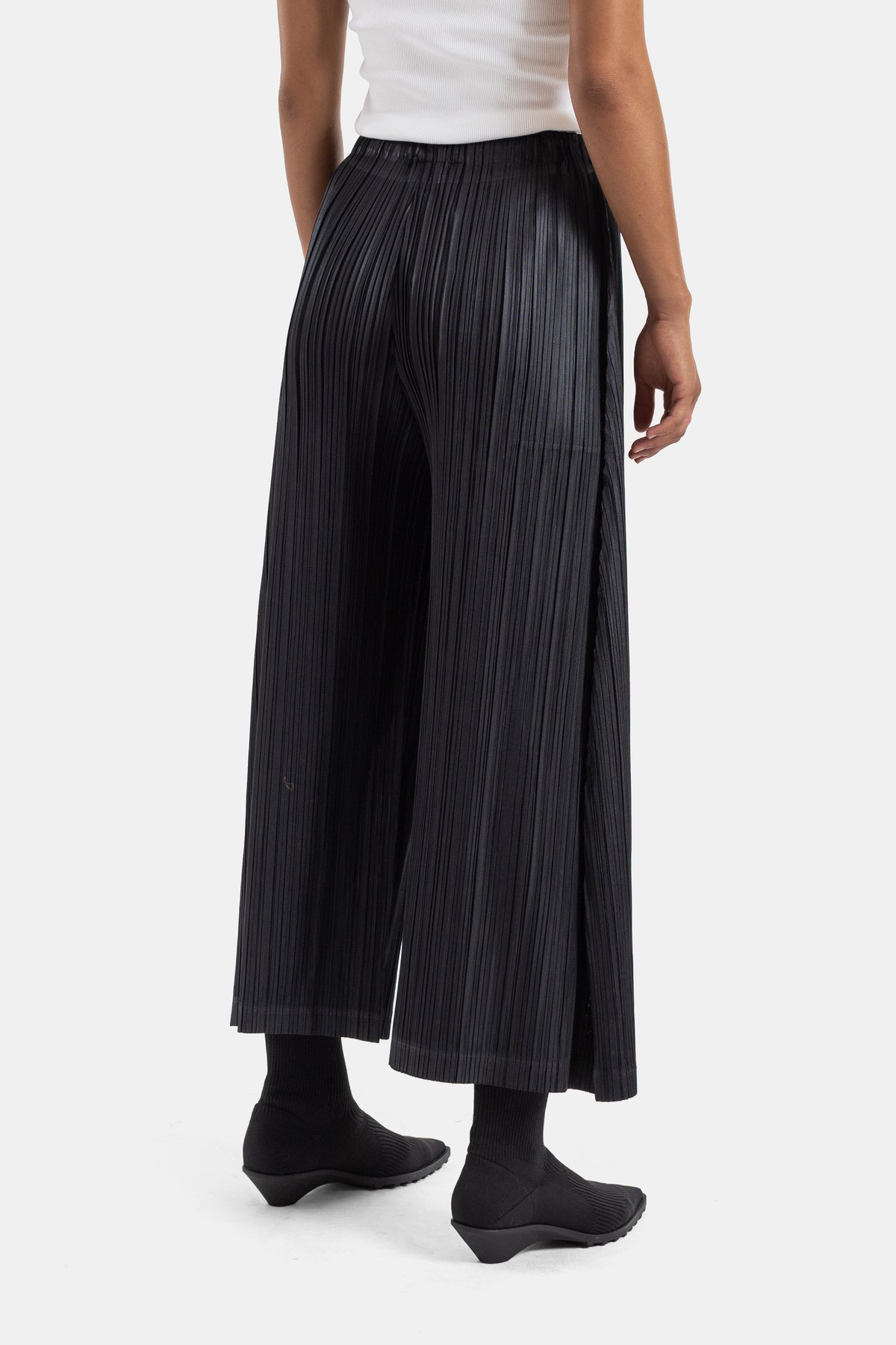 Vista trasera del pantalón plisado negro de Pleats Please Issey Miyake, detalle de caída para mujer
