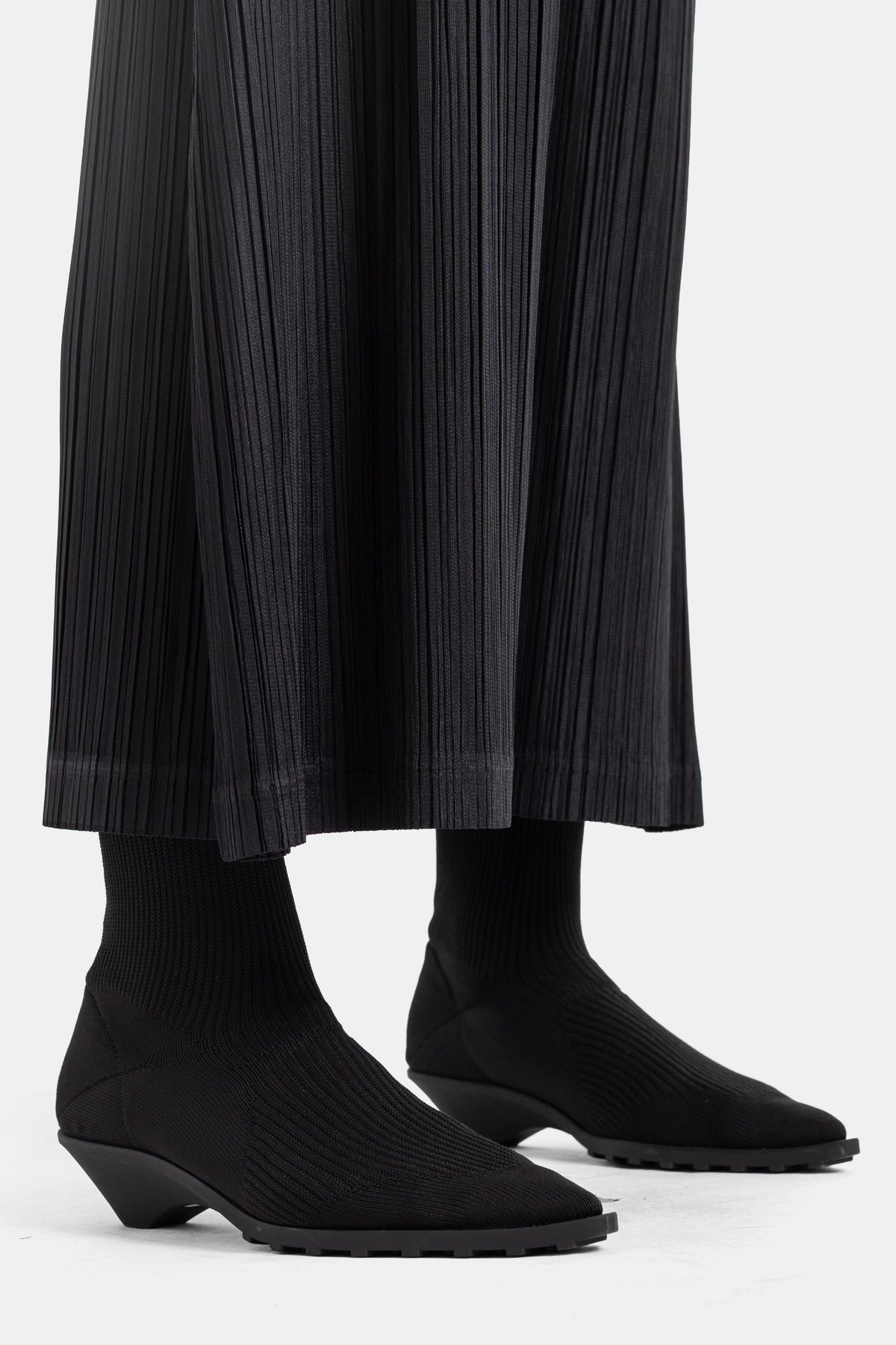 Botines de punto y pantalón plisado negro de Pleats Please Issey Miyake, zoom en el bajo para mujer