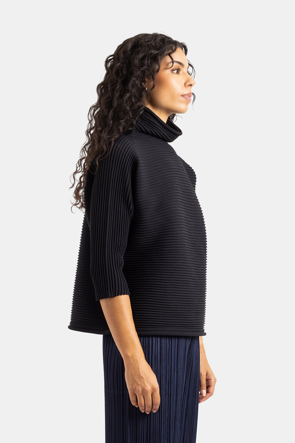 Top preto Pleats Please Issey Miyake de gola alta, corte oversize de perfil com textura plissada estruturada.