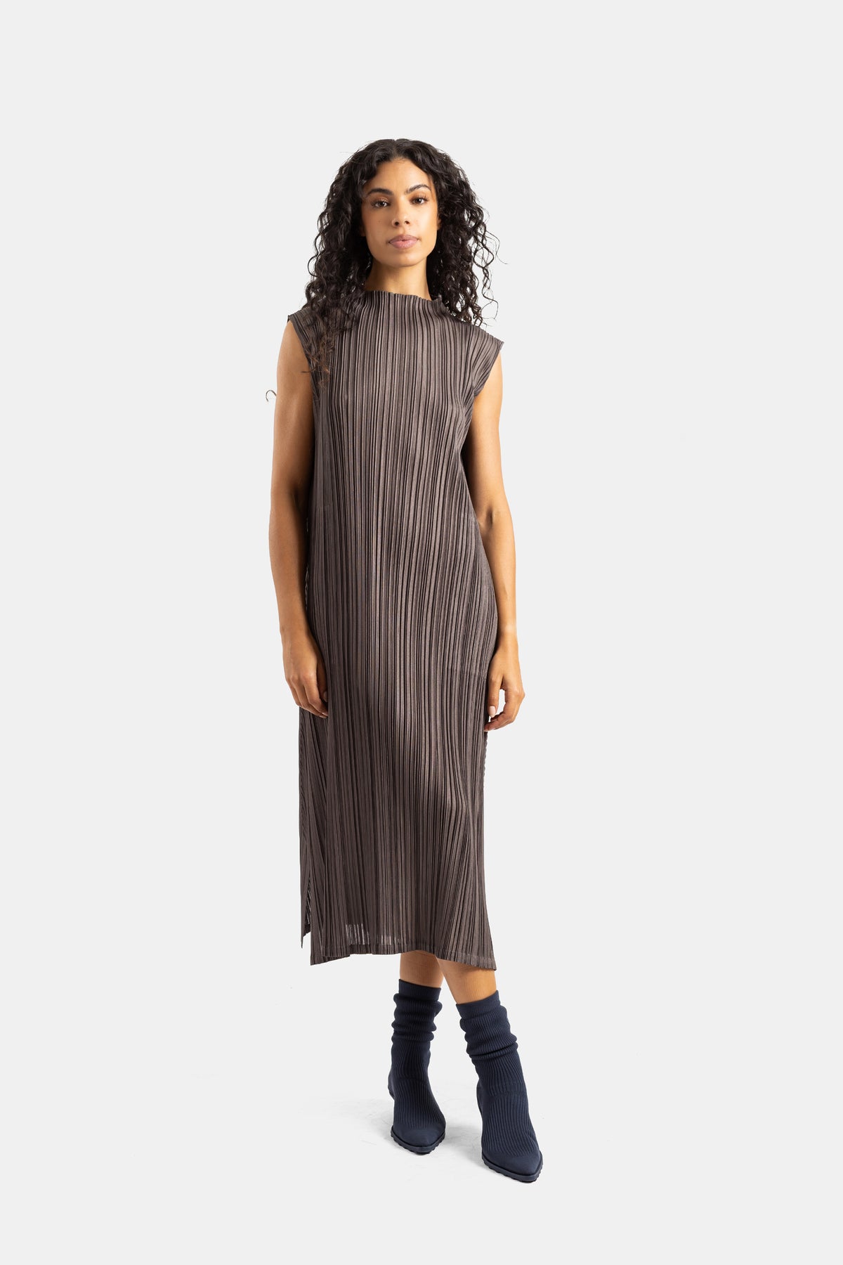 Pleats Please Issey Miyake Kleid in Taupe-Braun mit Navy-Boots getragen, gerade Silhouette von vorne.