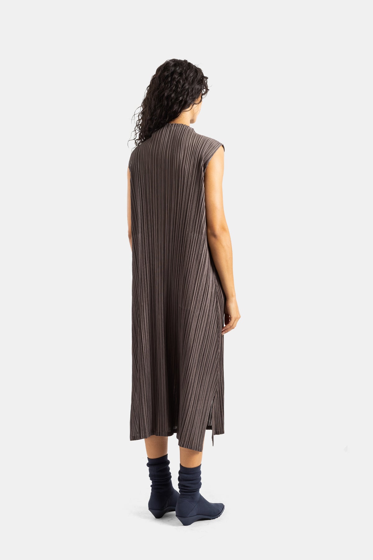 Rückansicht des rückenfreien, plissierten Kleids von Pleats Please Issey Miyake in fließendem Taupe-Braun.