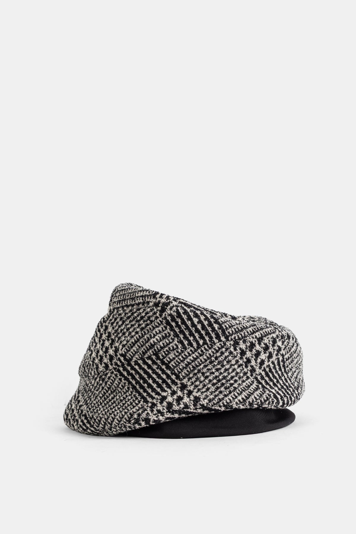 Berretto piatto Junya Watanabe in maglia jacquard principe di Galles bianco e nero, visiera in pelle nera.