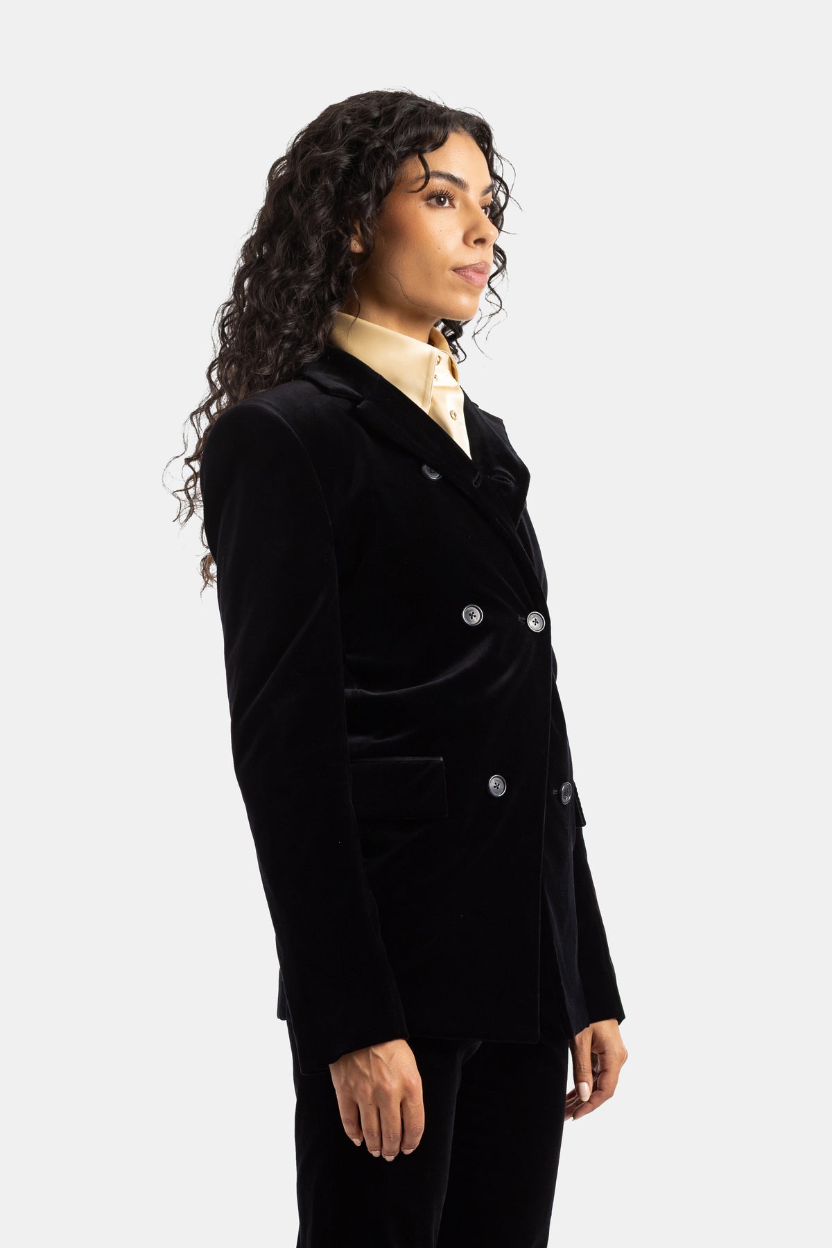 Khaite Rolo zwart fluwelen jasje in profiel, getailleerde pasvorm op een crème blouse, elegant silhouet