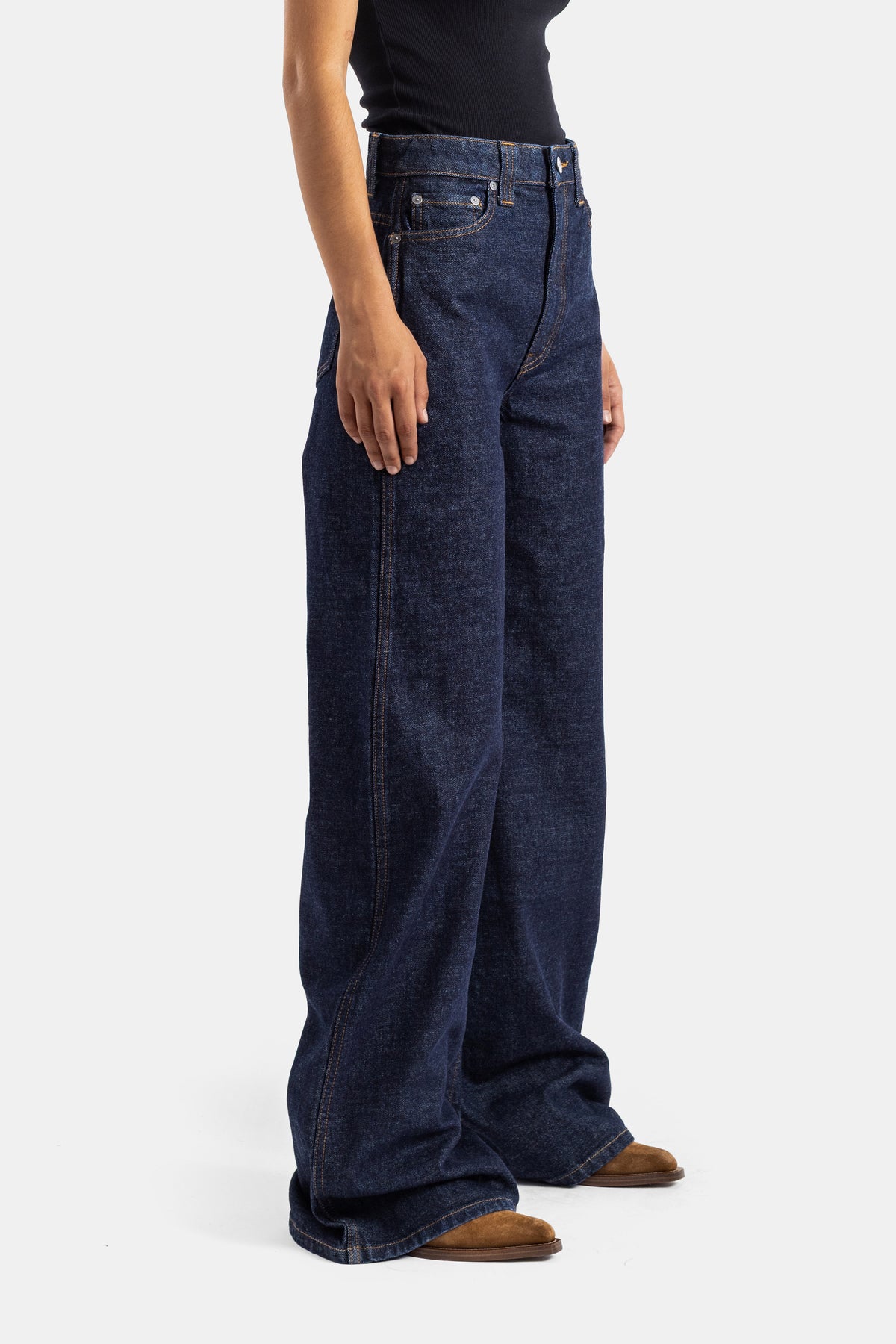 Khaite jean Dane évasé vue profil, silhouette large en denim rigide brut bleu nuit, coutures contrastées ocre