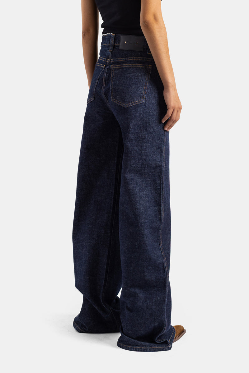 Khaite jean Dane dos trois quarts, poche arrière patch étiquette noire, denim brut bleu marine jambe ultra-large