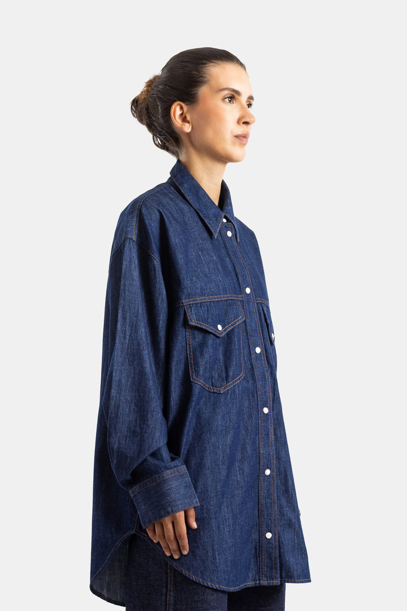 Khaite chemise denim oversize vue de profil, boutonnage pression blanc et coupe longue tombante
