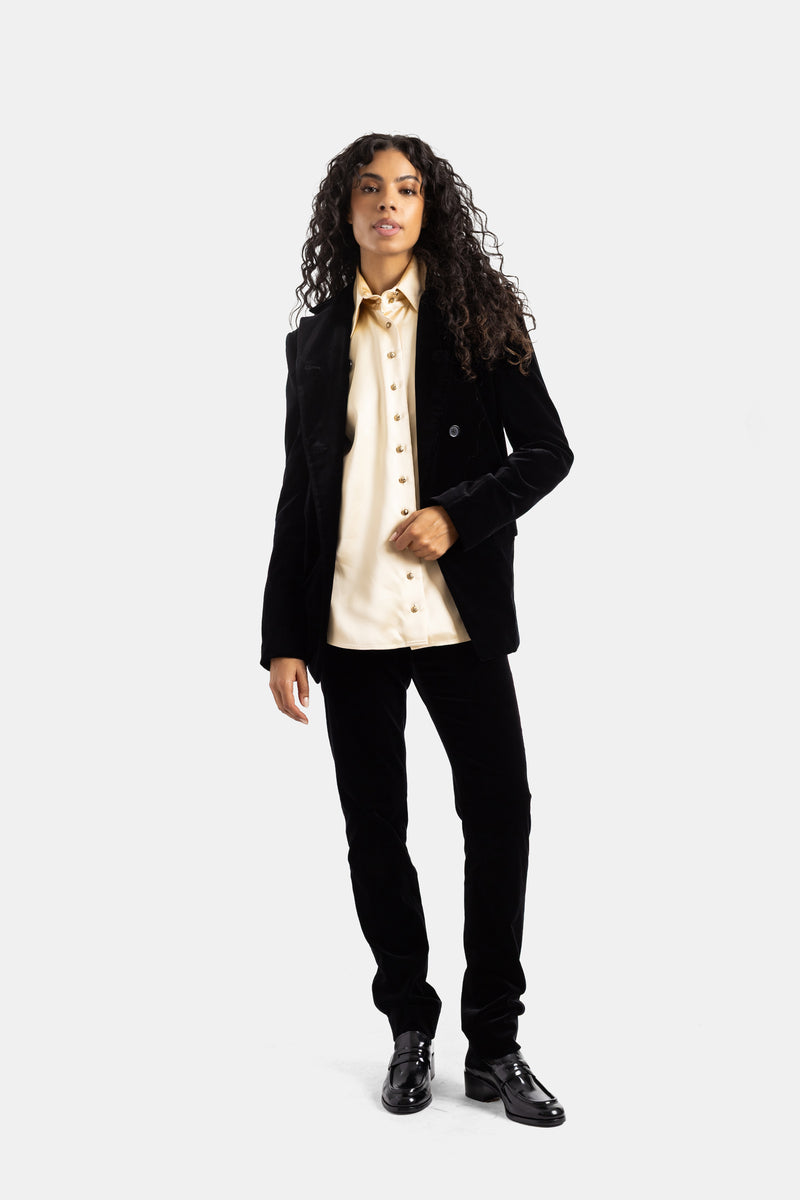 Completo Khaite in velluto nero donna con blazer strutturato, pantaloni slim e camicia avorio bottoni oro.