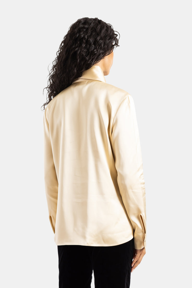 Camicia Ivy Khaite con schiena scoperta in raso champagne lucido, vista posteriore e pantaloni in velluto nero.
