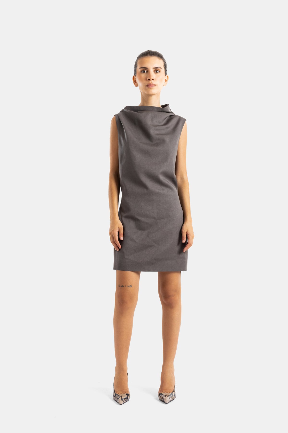 Khaite robe Astor mini sans manches tissu taupe, col asymétrique drapé, portée avec escarpins python nude
