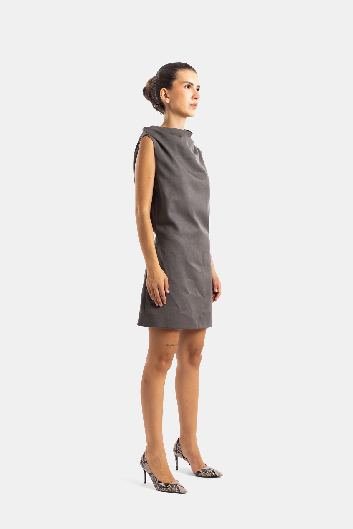 Khaite robe courte gris taupe vue de profil, silhouette droite et épaules structurées, portée avec escarpins python