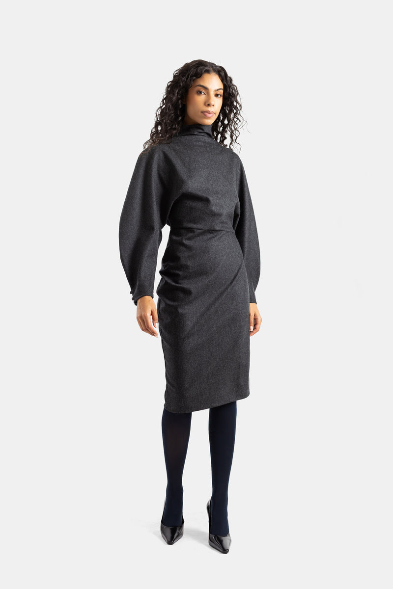 Khaite Harlin charcoal wool dress with voluminous sleeves and cinched waist, worn with black tights and pumps