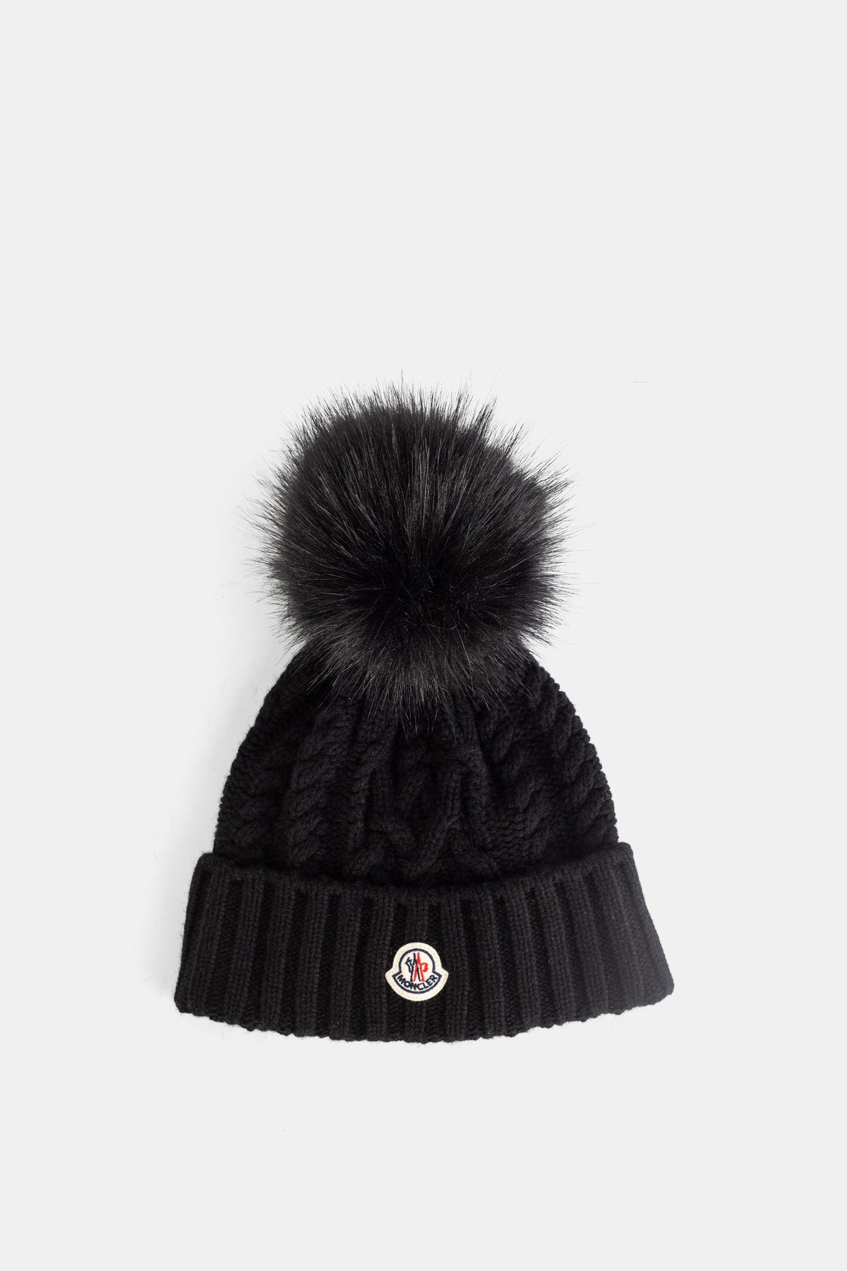 Moncler bonnet torsadé noir en maille câblée avec pompon en fourrure et revers côtelé
