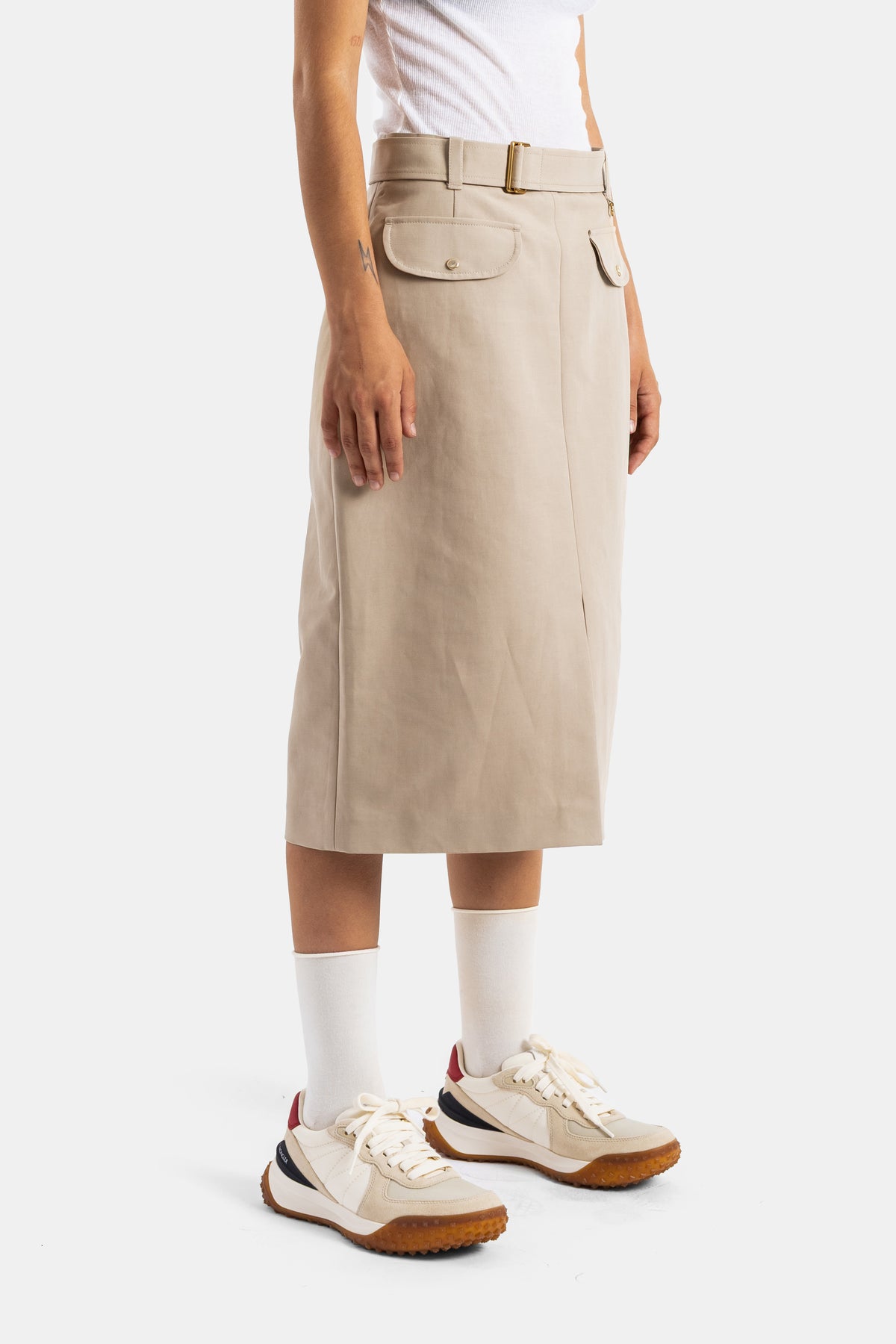 Moncler women's midi skirt in side profile with adjustable gold belt sand beige fabric and sport sneakers