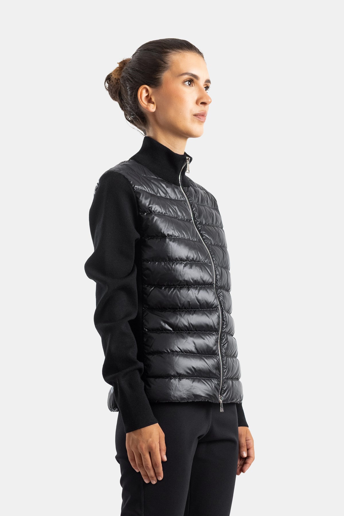 Cárdigan híbrido Moncler de mujer en vista lateral, cuerpo acolchado brillante y punto negro con cremallera.