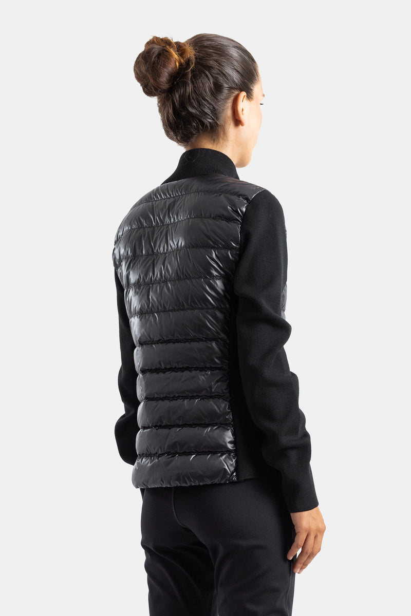Chaqueta híbrida Moncler de mujer vista de espalda, diseño acolchado brillante negro y punto acanalado detrás.