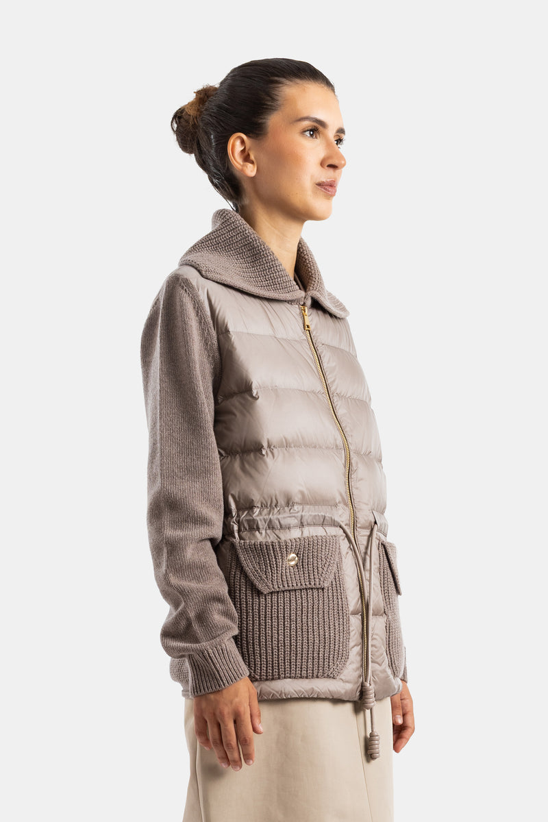 Chaqueta Moncler mujer perfil lateral acolchado taupe cremallera dorada mangas y bolsillos de punto.