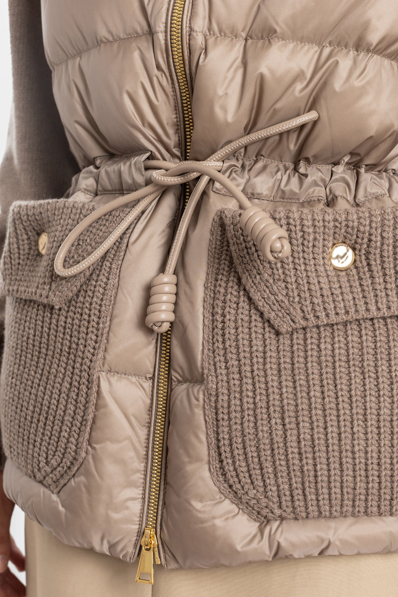 Detalle cárdigan Moncler acolchado bolsillos de punto cordón de cuero trenzado y cremallera dorada.