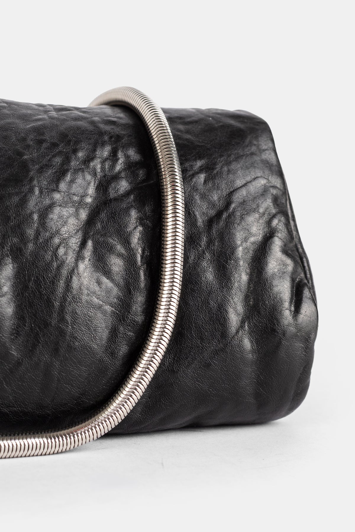 Rick Owens clutch cuir froissé noir gros plan, anse rigide spiralée argentée en métal brossé