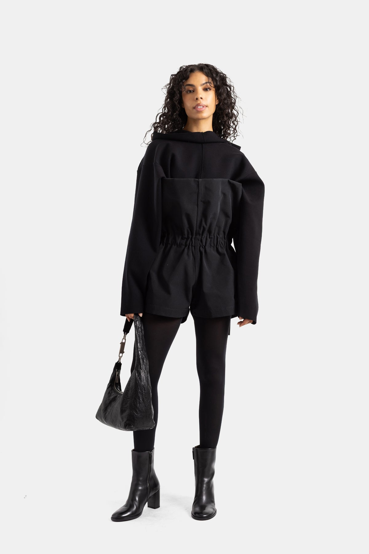 Black Rick Owens playsuit worn by a woman with leggings, heeled ankle boots and a creased leather hobo bag