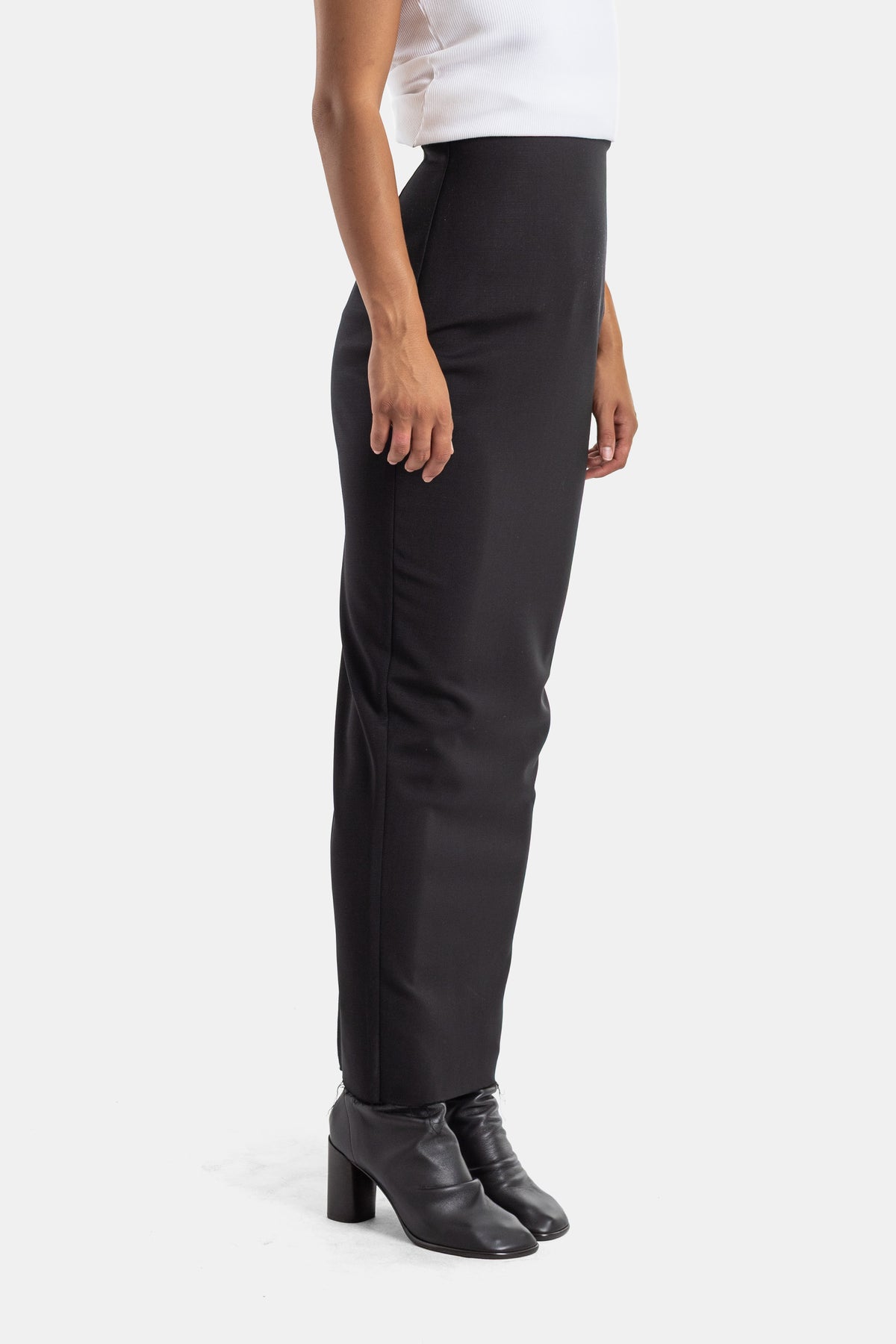 Gonna Pillar di Rick Owens vista di profilo, silhouette dritta a vita alta nera indossata con stivaletti con tacco.