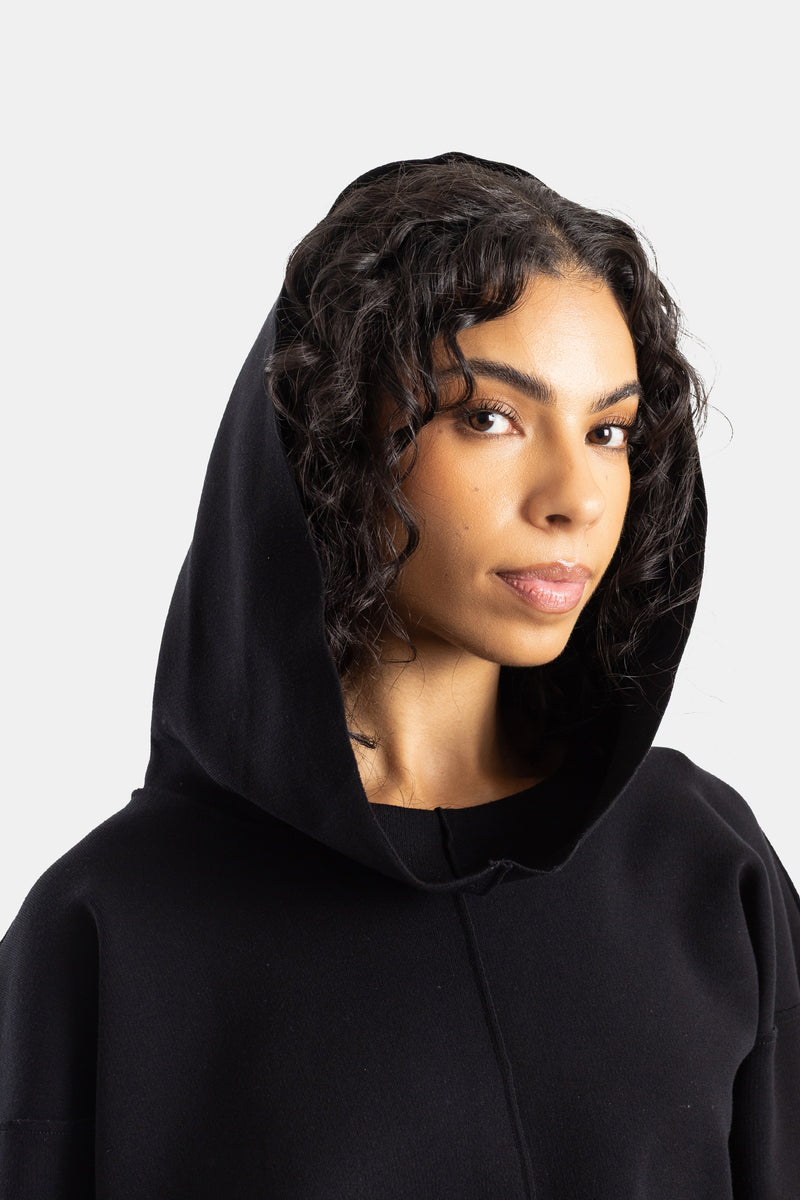 Rick Owens Damen-Hoodie in Schwarz im Nahporträt, Kapuze über lockigem Haar getragen, weiches Strickgewebe.