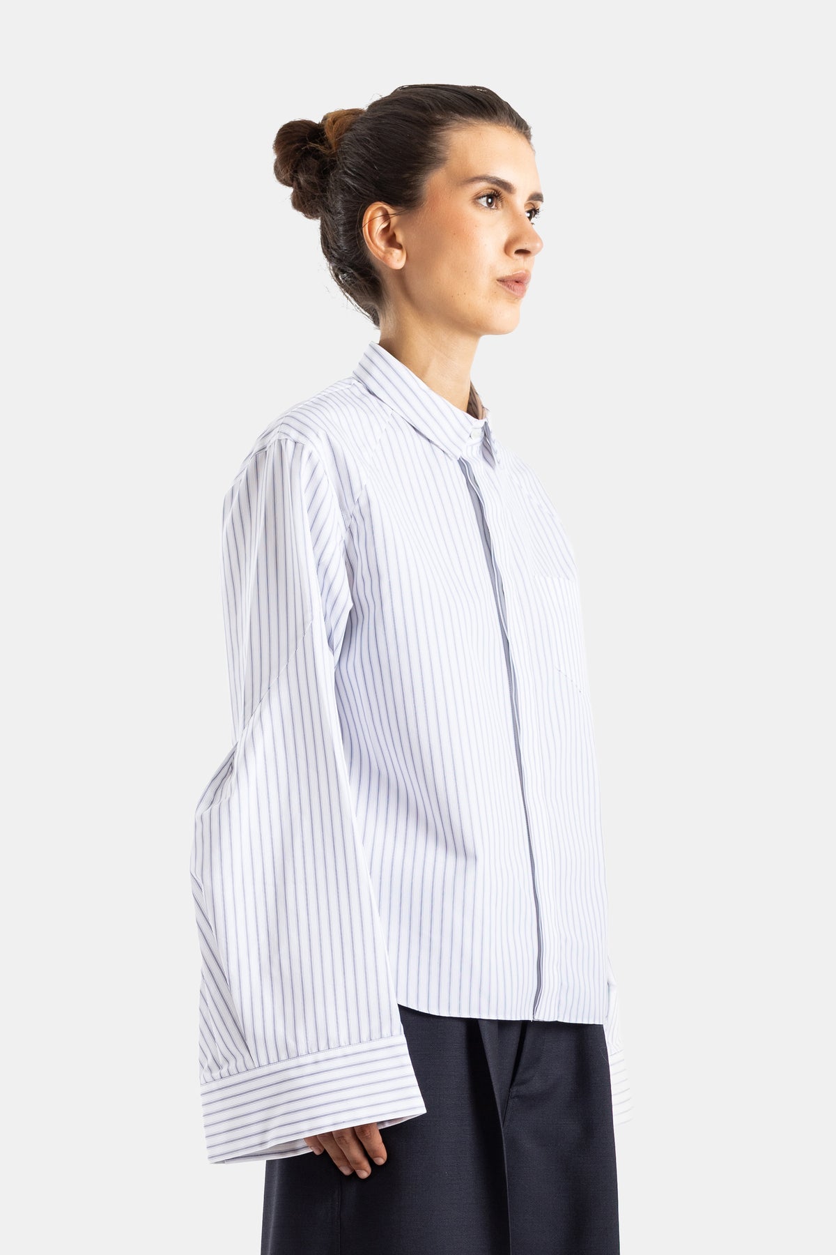 Sacai chemise popeline rayée vue profil coupe ample poignets larges tombants sur jupe longue marine