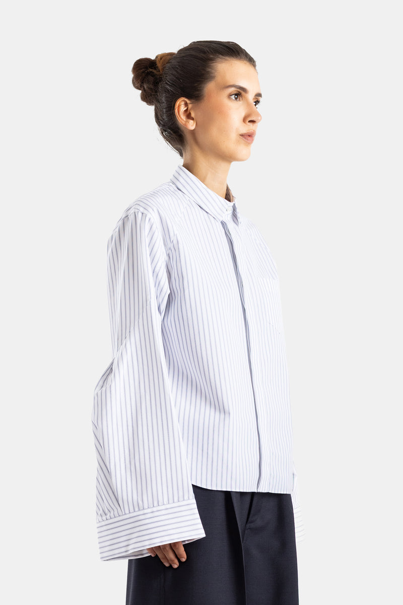 Sacai chemise popeline rayée vue profil coupe ample poignets larges tombants sur jupe longue marine