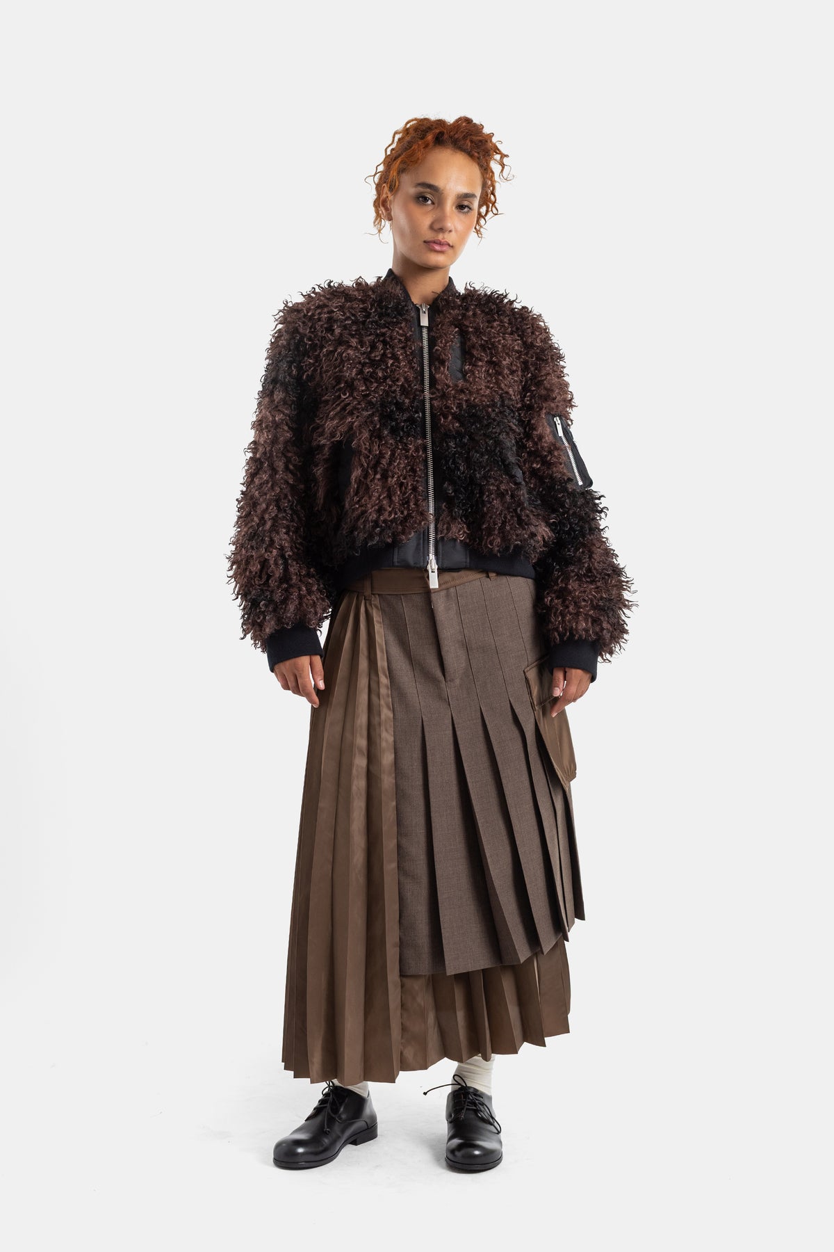 Saia plissada castanha Sacai com casaco bomber texturado, silhueta completa de frente e bainha assimétrica