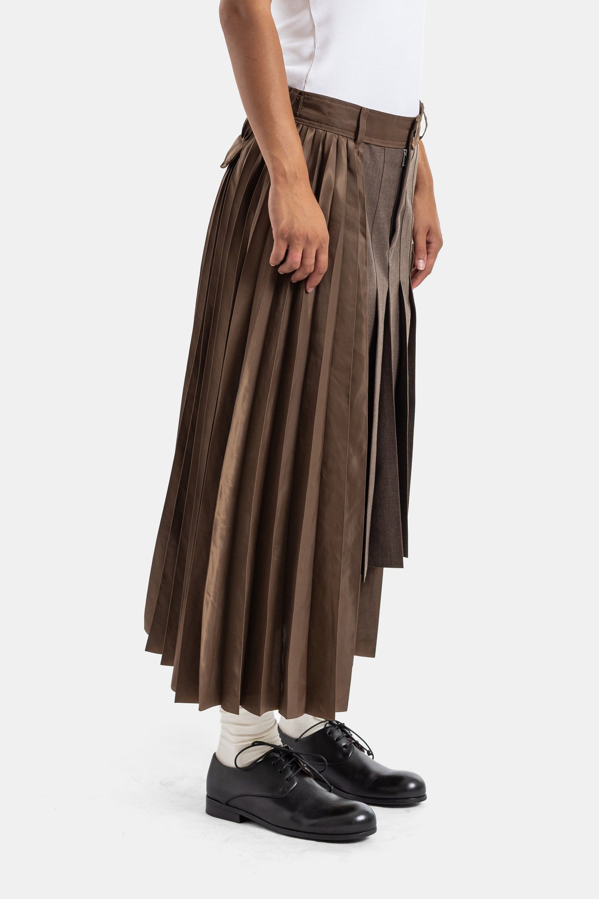 Saia plissada castanha Sacai vista de perfil com cinto de fivela D-ring e sobreposição assimétrica midi