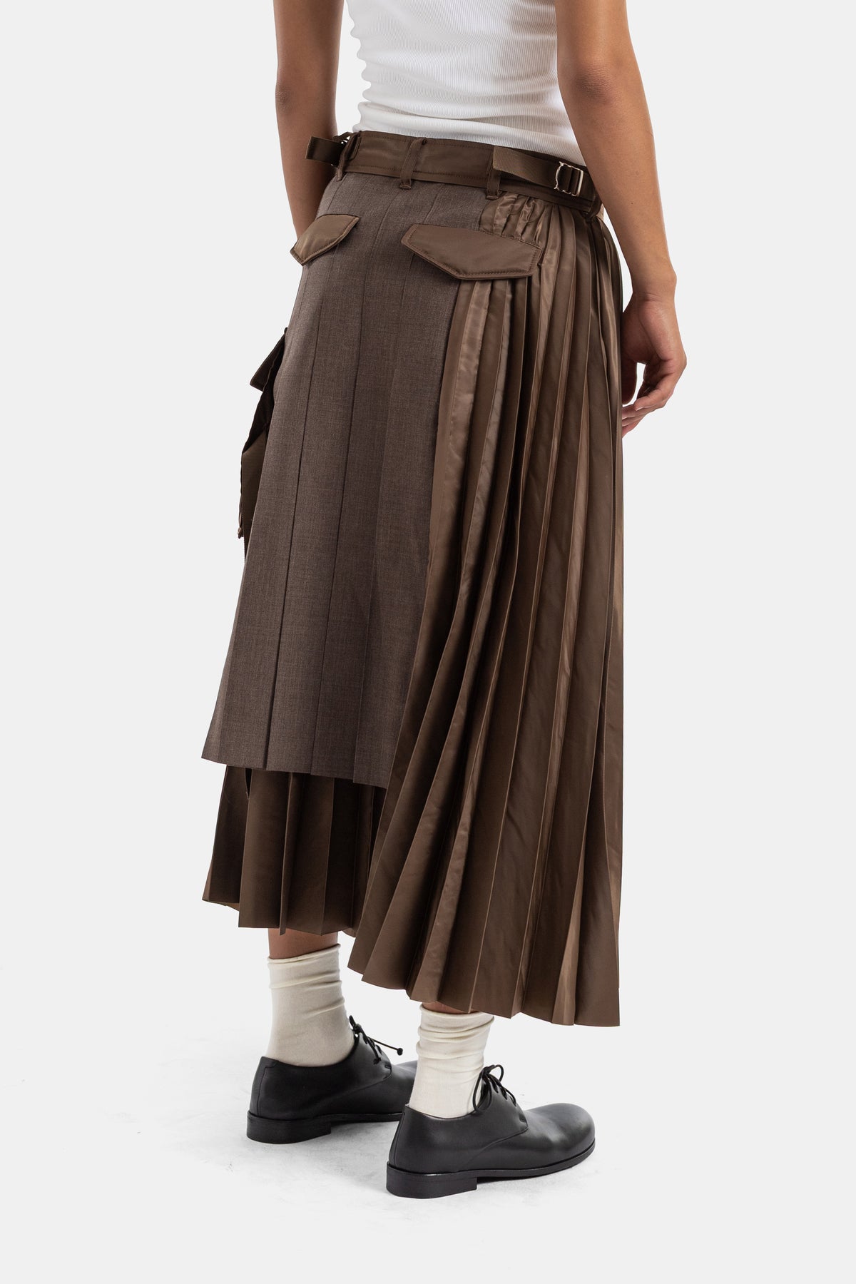 Saia híbrida plissada castanha Sacai vista de costas, com bolsos cargo contrastantes e cinto com fivela de metal